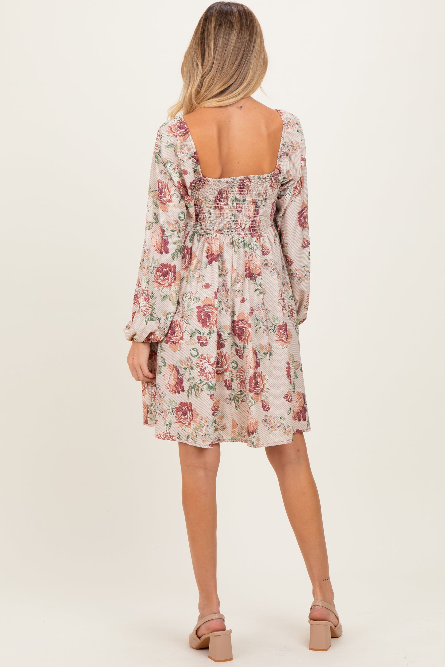 woman wearing a floral print smocked back maternity dress with long sleeves and a flowy skirt