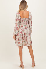 woman wearing a floral print smocked back maternity dress with long sleeves and a flowy skirt