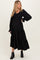 woman wearing a black maternity maxi dress with long sleeves and a tiered skirt, showing her baby bump