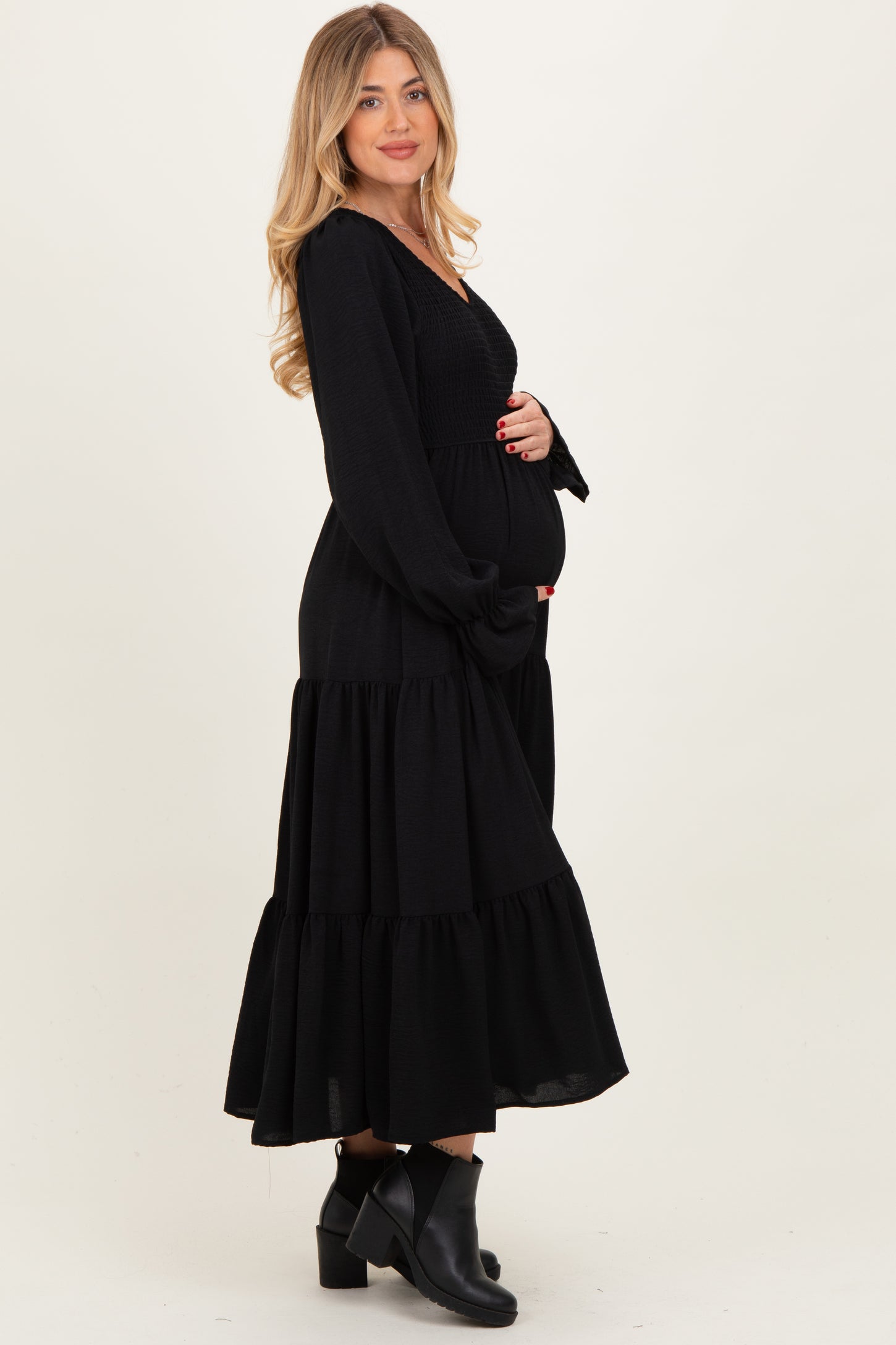 woman wearing a black maternity dress with long sleeves and tiered skirt, highlighting her baby bump