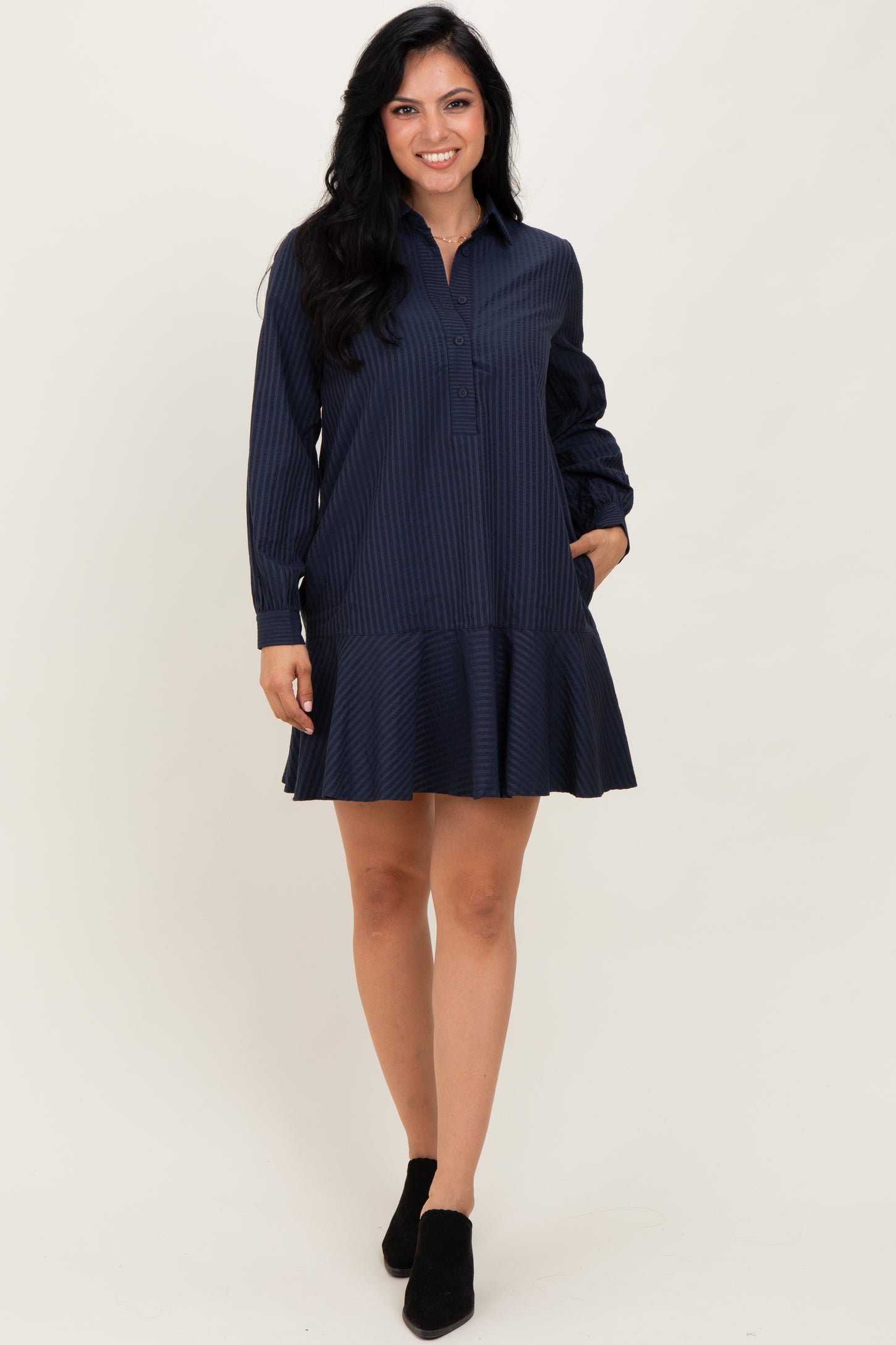 woman wearing a navy striped long sleeve shirt dress with a flared hem and pockets, paired with black ankle boots