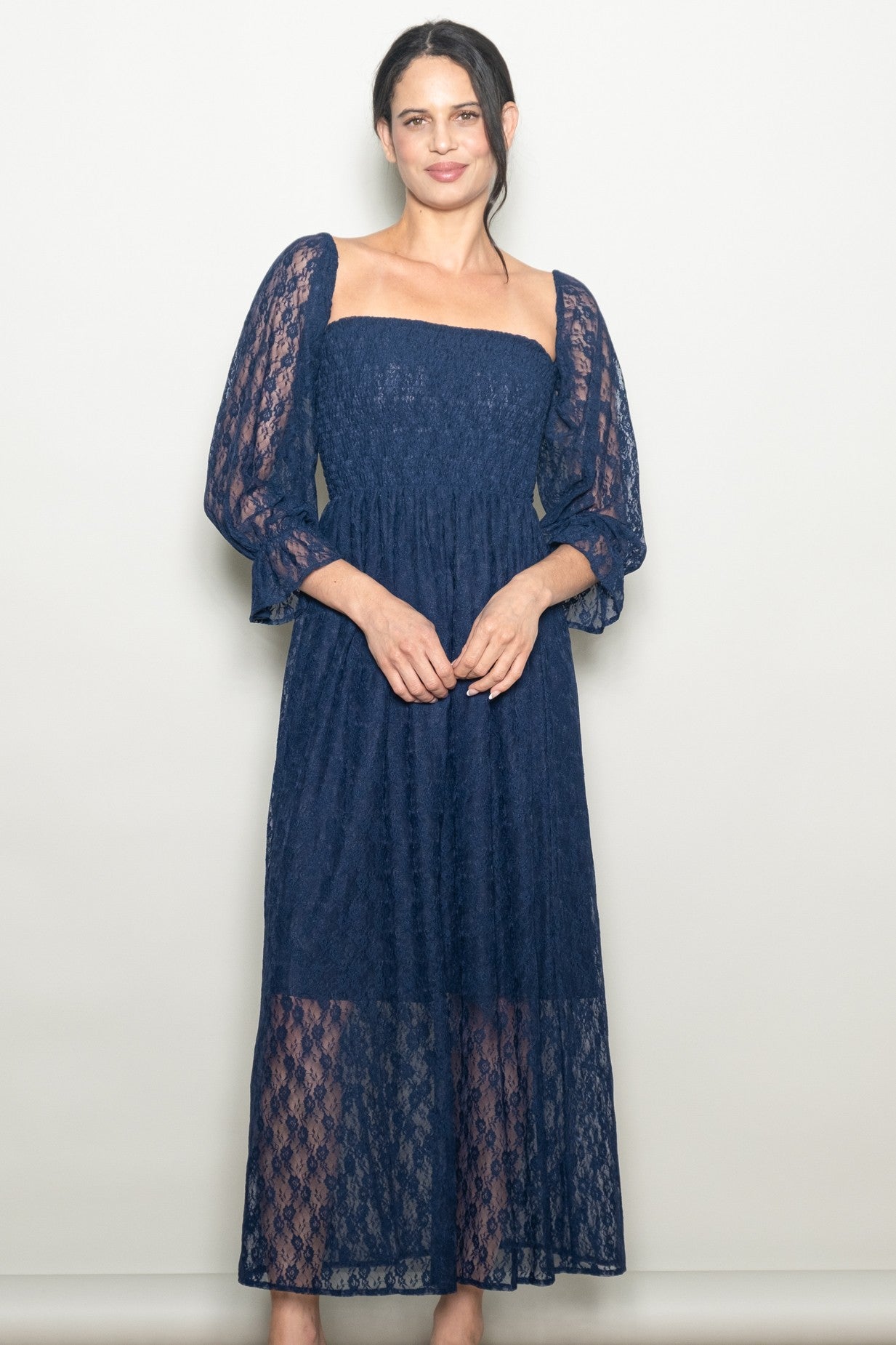 woman wearing a navy lace maxi dress with puff sleeves and a fitted bodice