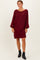 woman wearing a burgundy cable knit sweater dress with balloon sleeves and black ankle boots