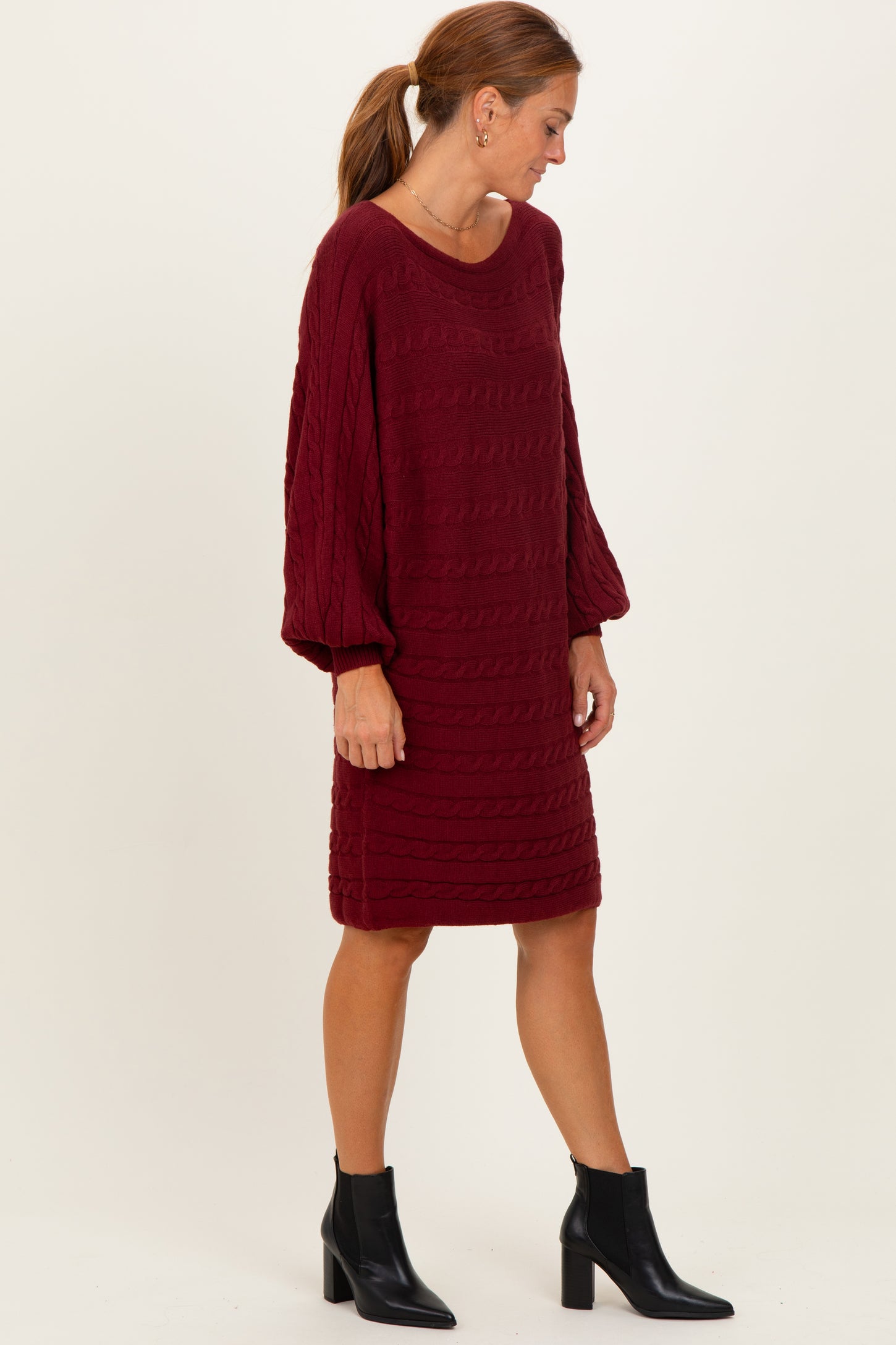 woman wearing a burgundy cable knit sweater dress with balloon sleeves and ankle boots