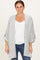 woman wearing a light gray cardigan with rolled sleeves over a white top and dark jeans