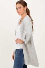woman wearing a light gray open cardigan with rolled sleeves and a white top, styled with blue jeans