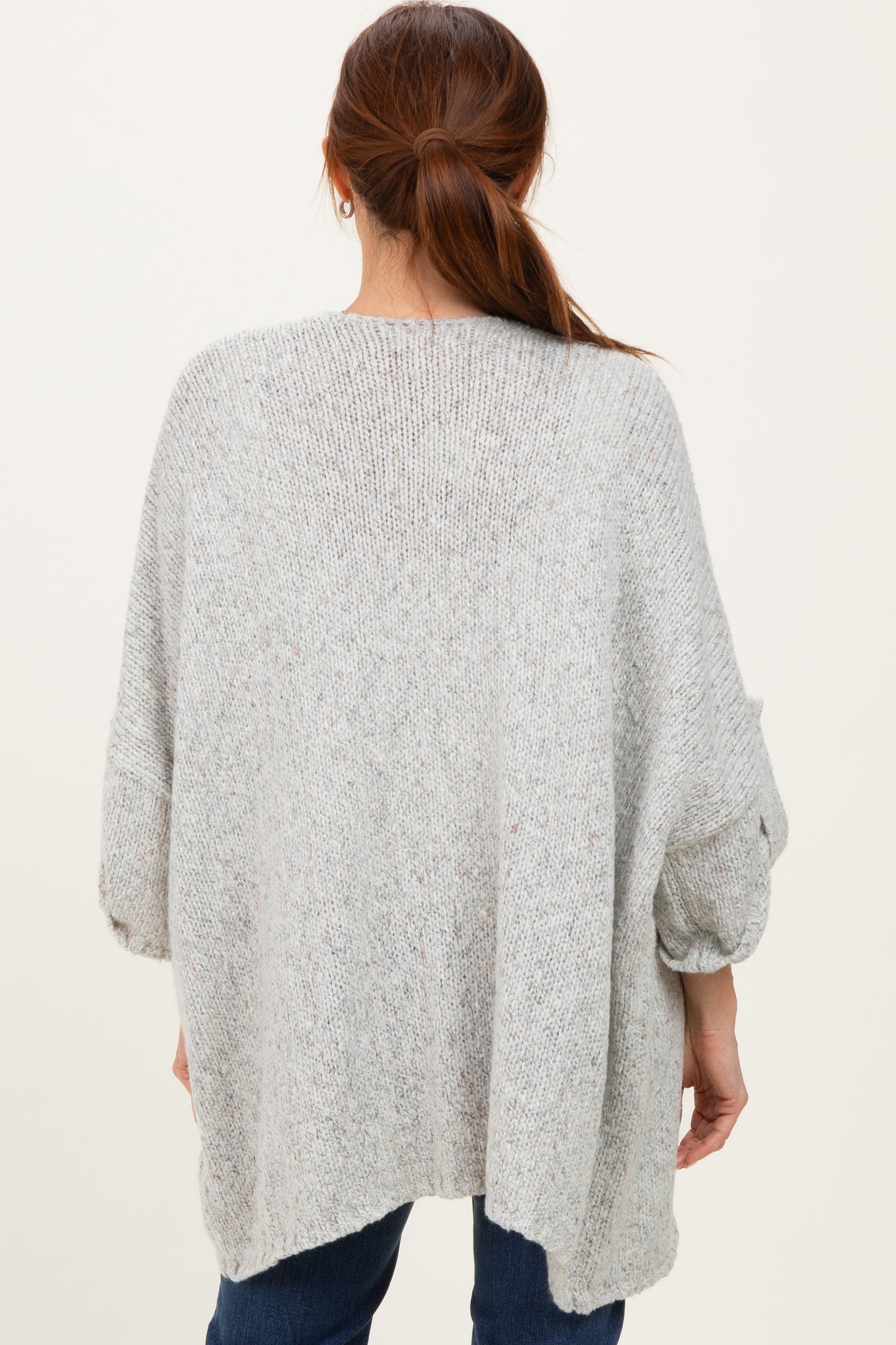 woman wearing a loose-fitting gray oversized sweater with three-quarter sleeves and a relaxed fit