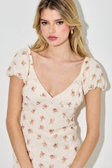 woman wearing a light pink floral midi dress with puff sleeves and a deep v-neckline