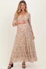 woman wearing a flowy beige floral maternity maxi dress with three-quarter sleeves and a visible baby bump