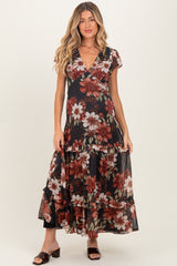 woman wearing a black floral maxi maternity dress with ruffled layers and cap sleeves, showcasing her baby bump