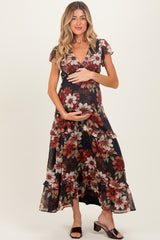 woman wearing a black floral maternity maxi dress and holding her baby bump