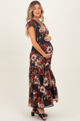 woman wearing a black floral maternity maxi dress with short sleeves and a side slit, holding her baby bump