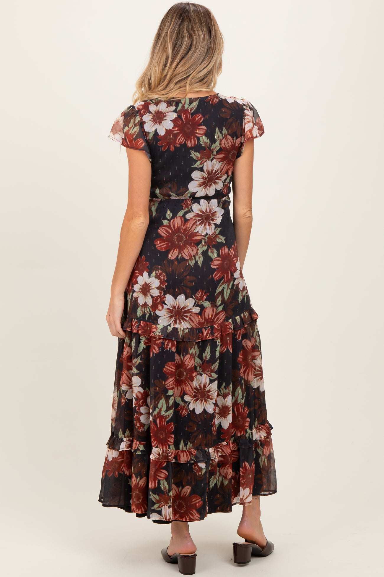 woman wearing a black floral maternity maxi dress with cap sleeves and a tiered skirt