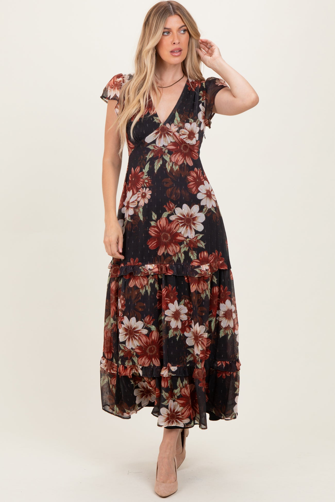 woman wearing a black floral maxi dress with ruffled sleeves and a tiered skirt