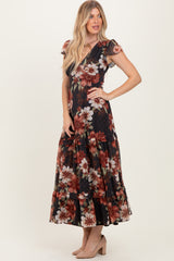 woman wearing a black floral maxi dress with ruffle details and short sleeves, standing with one hand on her hip