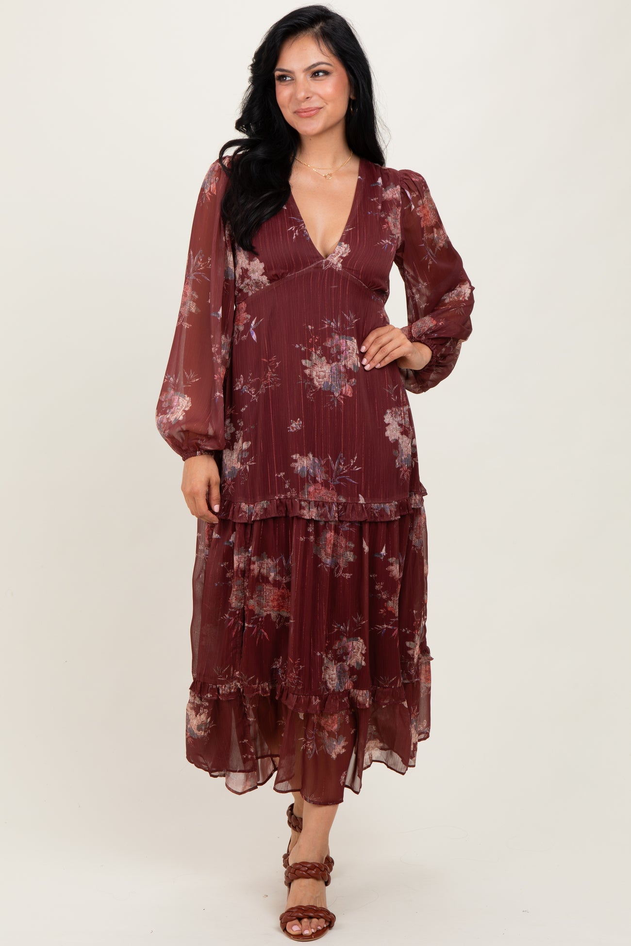woman wearing a burgundy floral maxi dress with long sleeves and layered ruffles