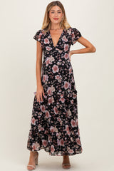 woman wearing a floral maxi maternity dress with short ruffled sleeves and a deep v-neck, posing with one hand on hip