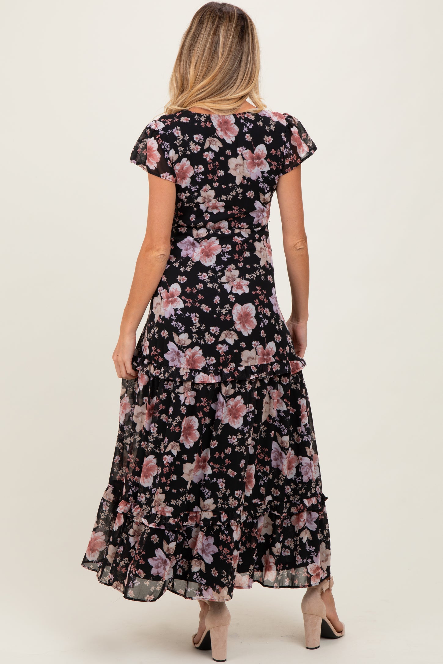 woman wearing a black floral maternity maxi dress with ruffle details, showing the back view