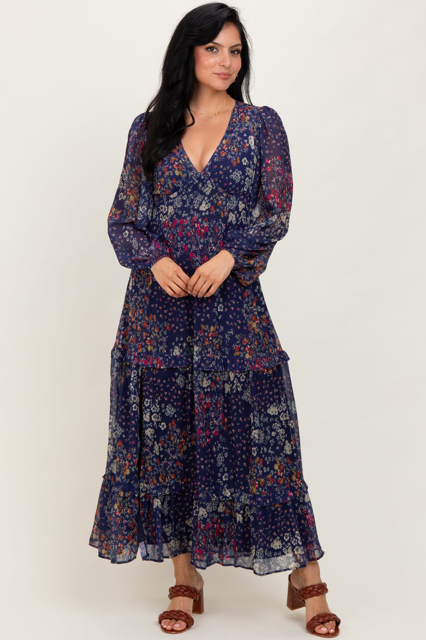 woman wearing a long sleeve navy floral maxi dress with a tiered skirt and a v-neckline