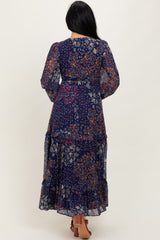 woman wearing a navy floral maxi dress with long sleeves and ruffled hem from the back