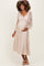 woman wearing a beige floral lace maternity dress with long puff sleeves and a baby bump visible