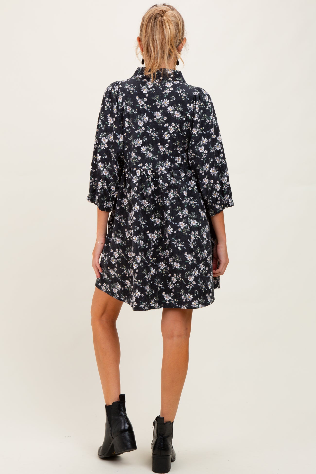 woman wearing a black floral maternity dress with three-quarter sleeves and a flowy silhouette, showing a baby bump