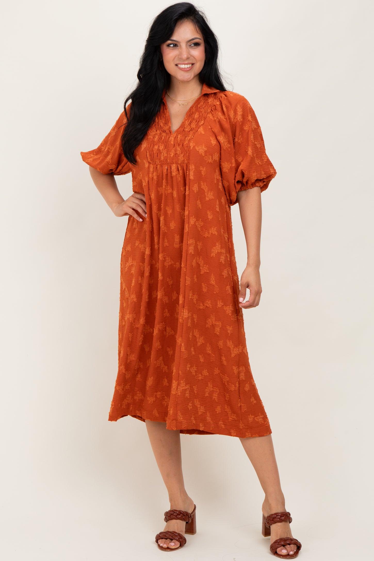 woman wearing an orange midi dress with a v-neck and puff sleeves, featuring a floral pattern