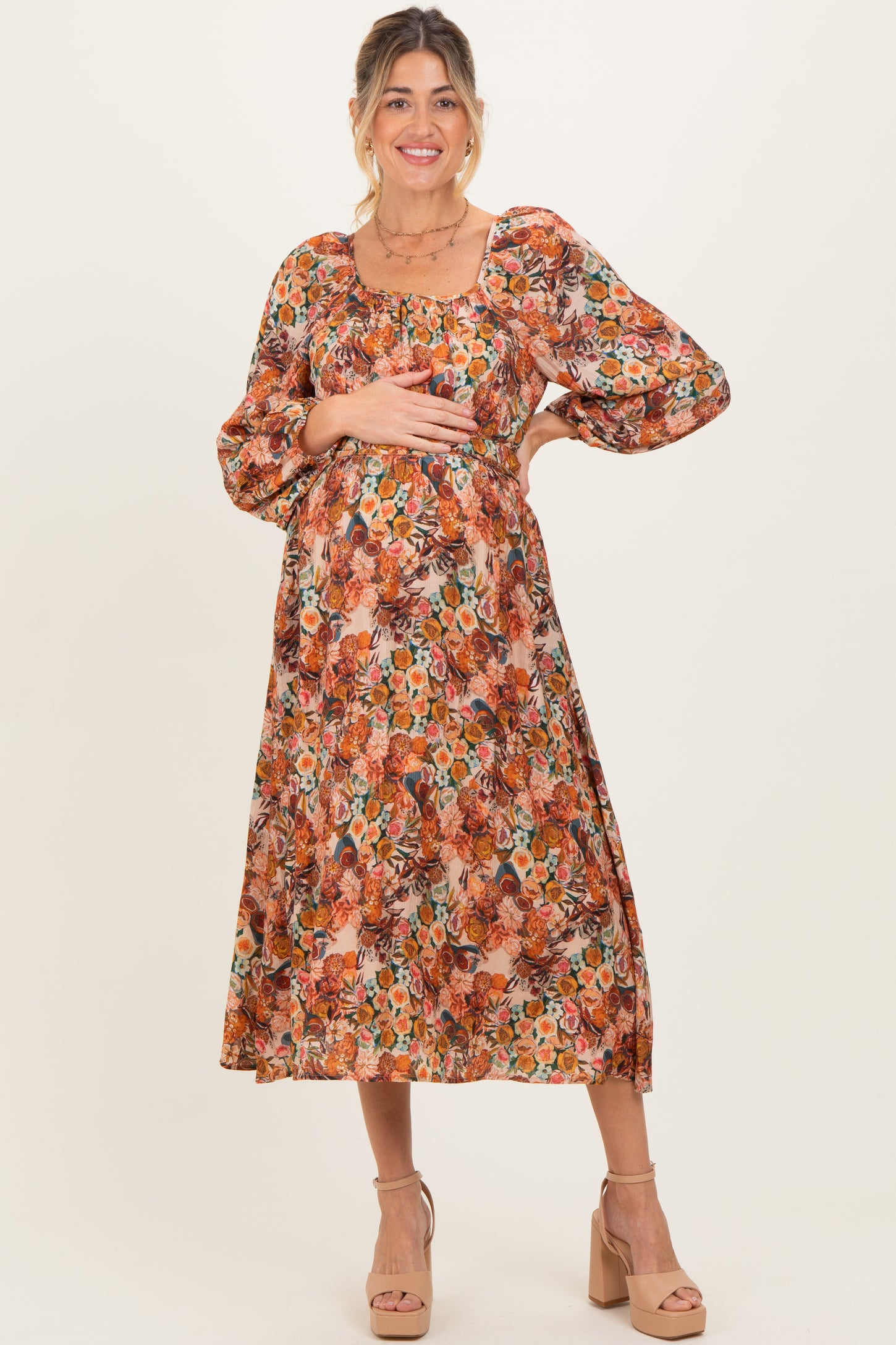 woman wearing a floral print maternity dress with puff sleeves and holding her baby bump