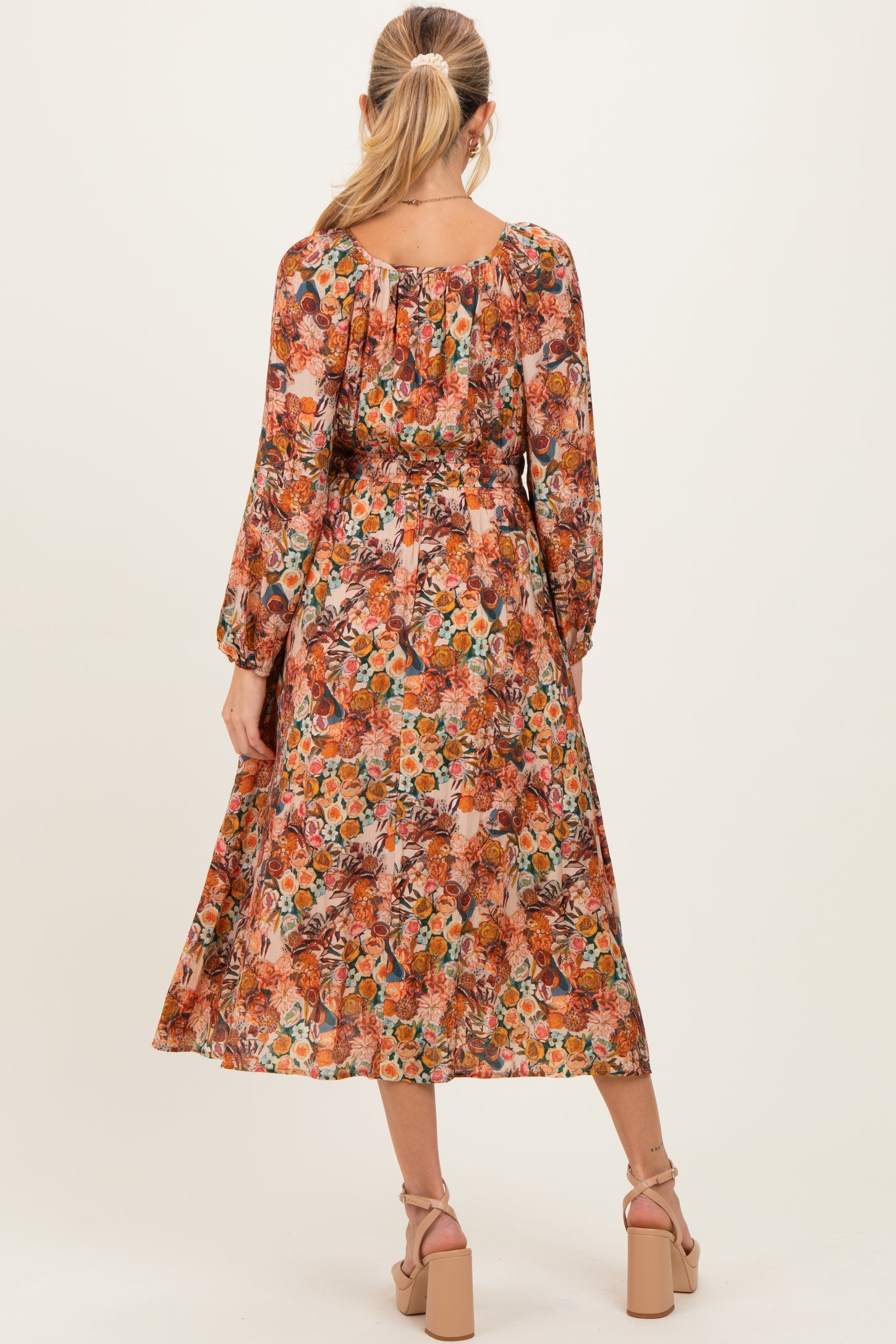 woman wearing a floral maternity maxi dress with long sleeves and a fitted waist, showing a baby bump from the back