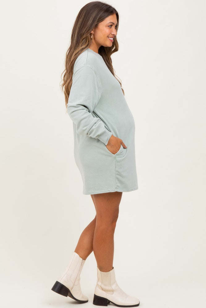 woman wearing a light green long sleeve maternity dress with pockets and a visible baby bump