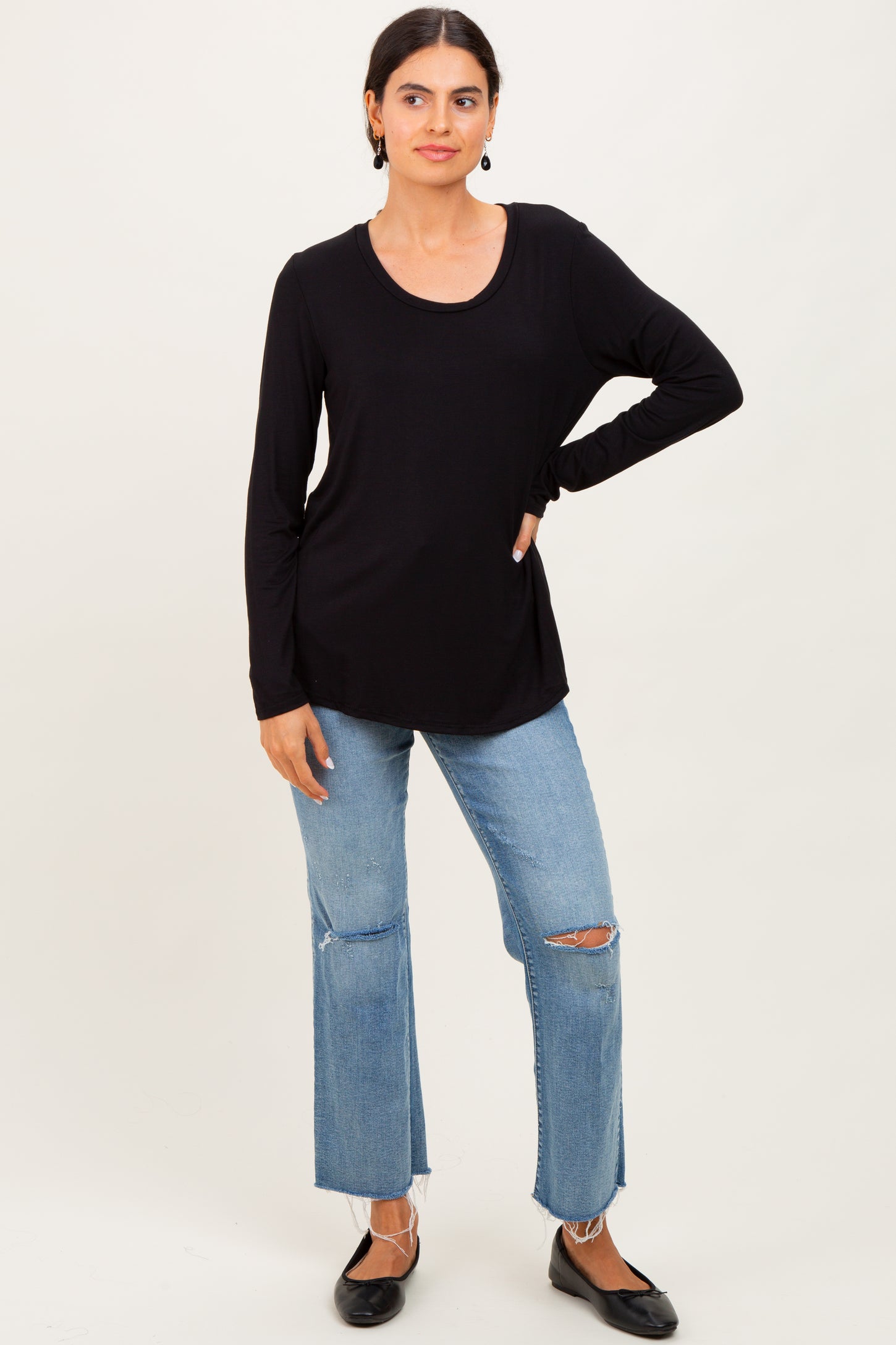woman wearing a black long sleeve top and light blue ripped jeans