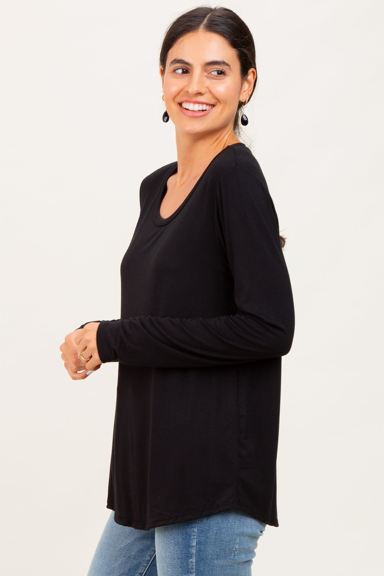 woman wearing a black long sleeve top with a scoop neckline and relaxed fit, paired with light blue jeans