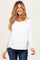 woman wearing a white long sleeve maternity top and showing her baby bump