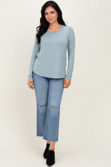 woman wearing a light teal long sleeve top and distressed light wash flared jeans with black ankle boots