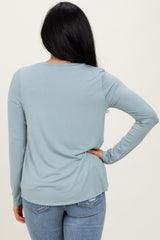 woman wearing a light blue long sleeve top with a relaxed fit and round neck, seen from the back