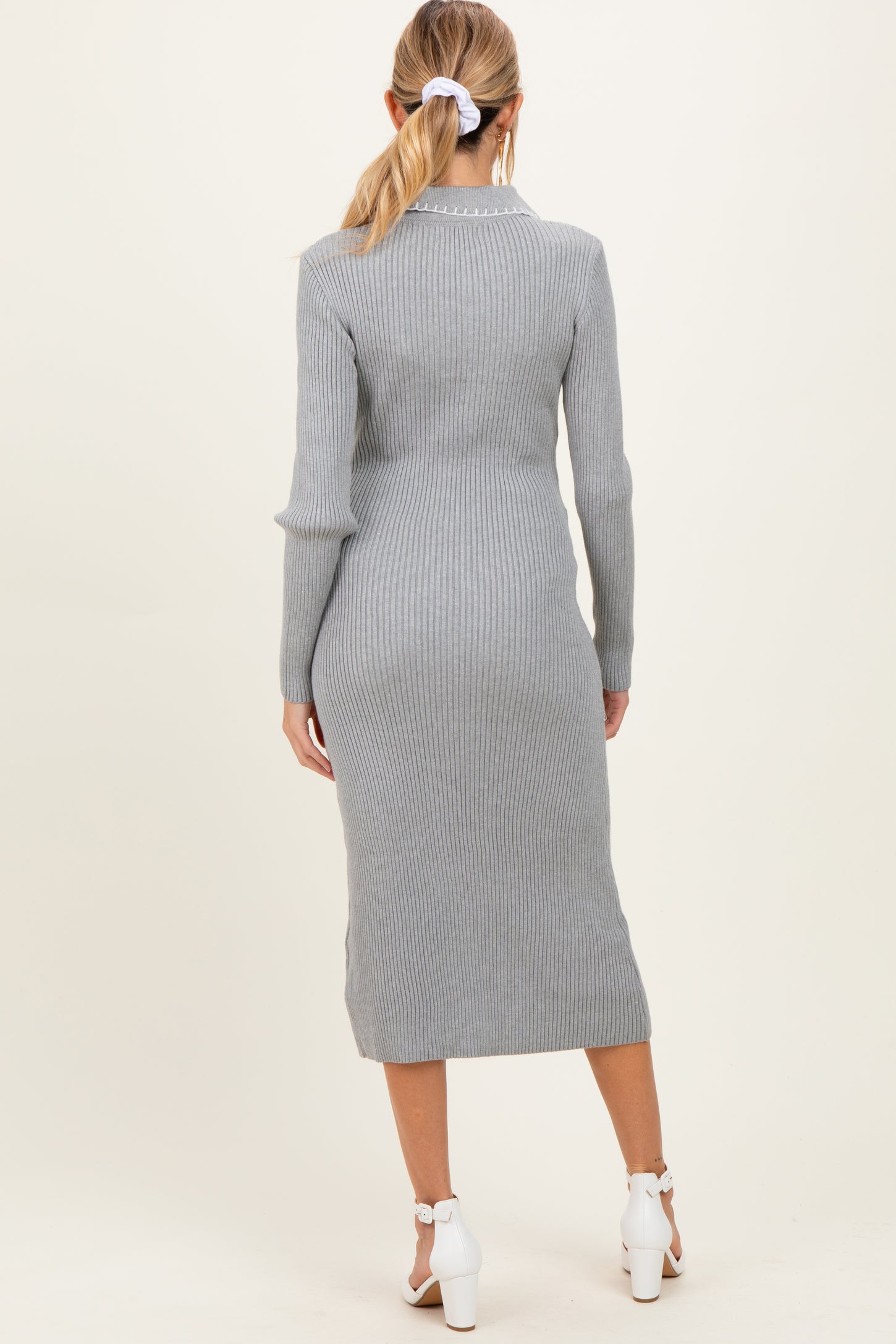 woman wearing a light grey ribbed maternity dress, view from the back, with a fitted silhouette and mid-calf length
