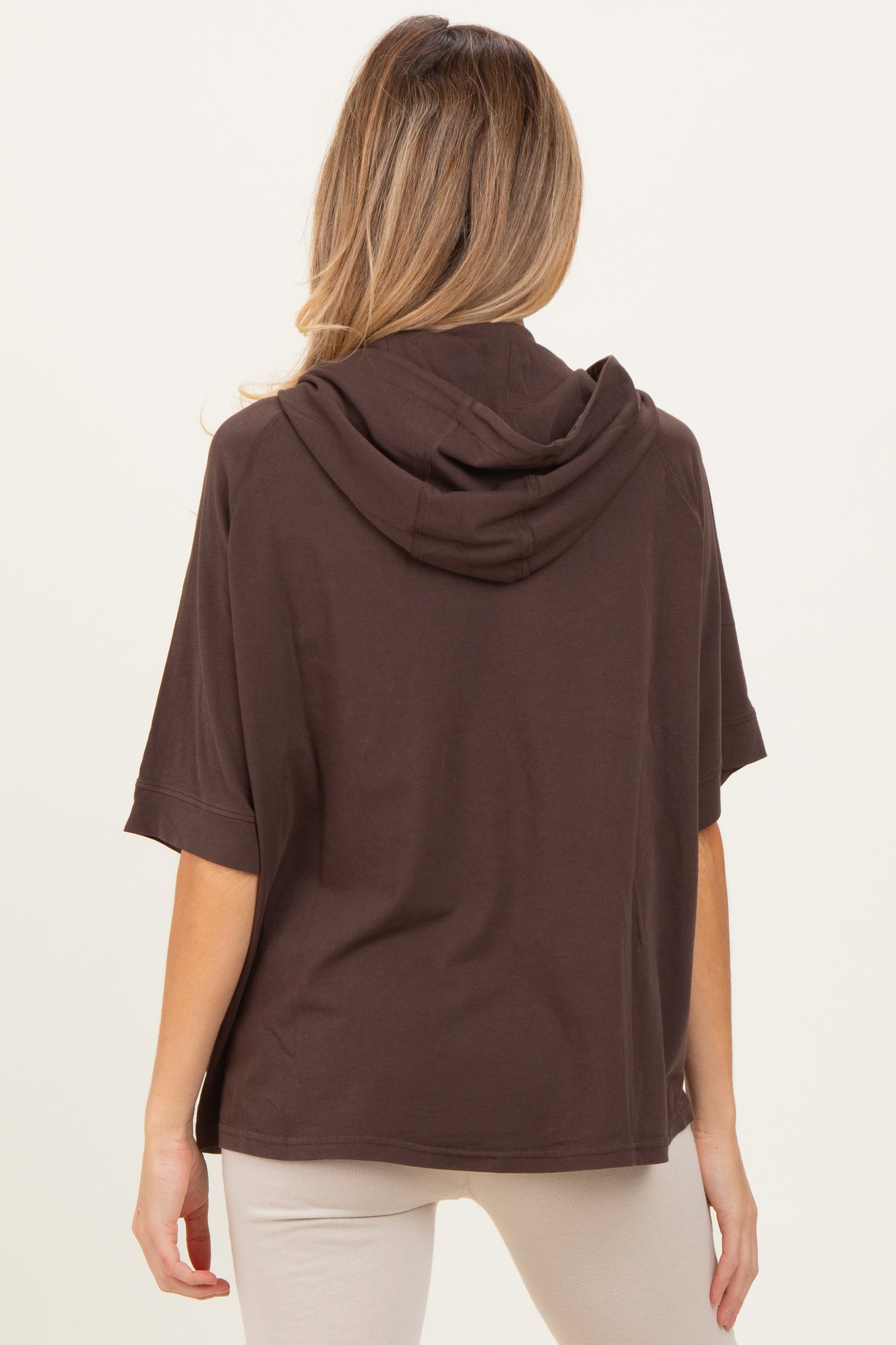 woman wearing a brown short sleeve maternity hoodie with a relaxed fit, viewed from the back