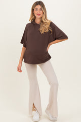 woman wearing a brown maternity hoodie with a relaxed fit and beige flared pants, showing her baby bump