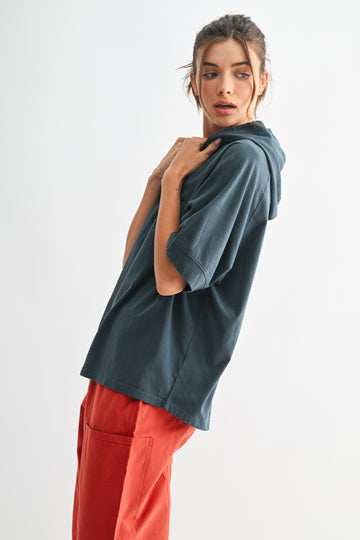 woman wearing a teal oversized hoodie with short sleeves and red cargo pants