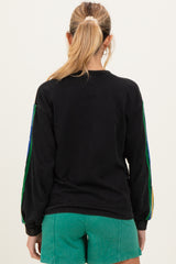 woman wearing a black maternity sweatshirt with colorful striped sleeves and styled with green shorts
