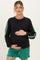 woman wearing a black maternity sweatshirt with colorful stripes on the sleeves and holding her baby bump
