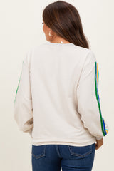 woman wearing a light beige long sleeve maternity sweatshirt with colorful striped detailing on the sleeves