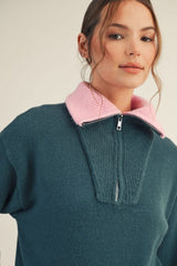 woman wearing a teal pullover sweater with a pink collar and half zipper detail