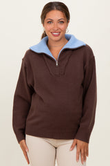 woman wearing a brown maternity pullover sweater with a light blue collar and zipper detail