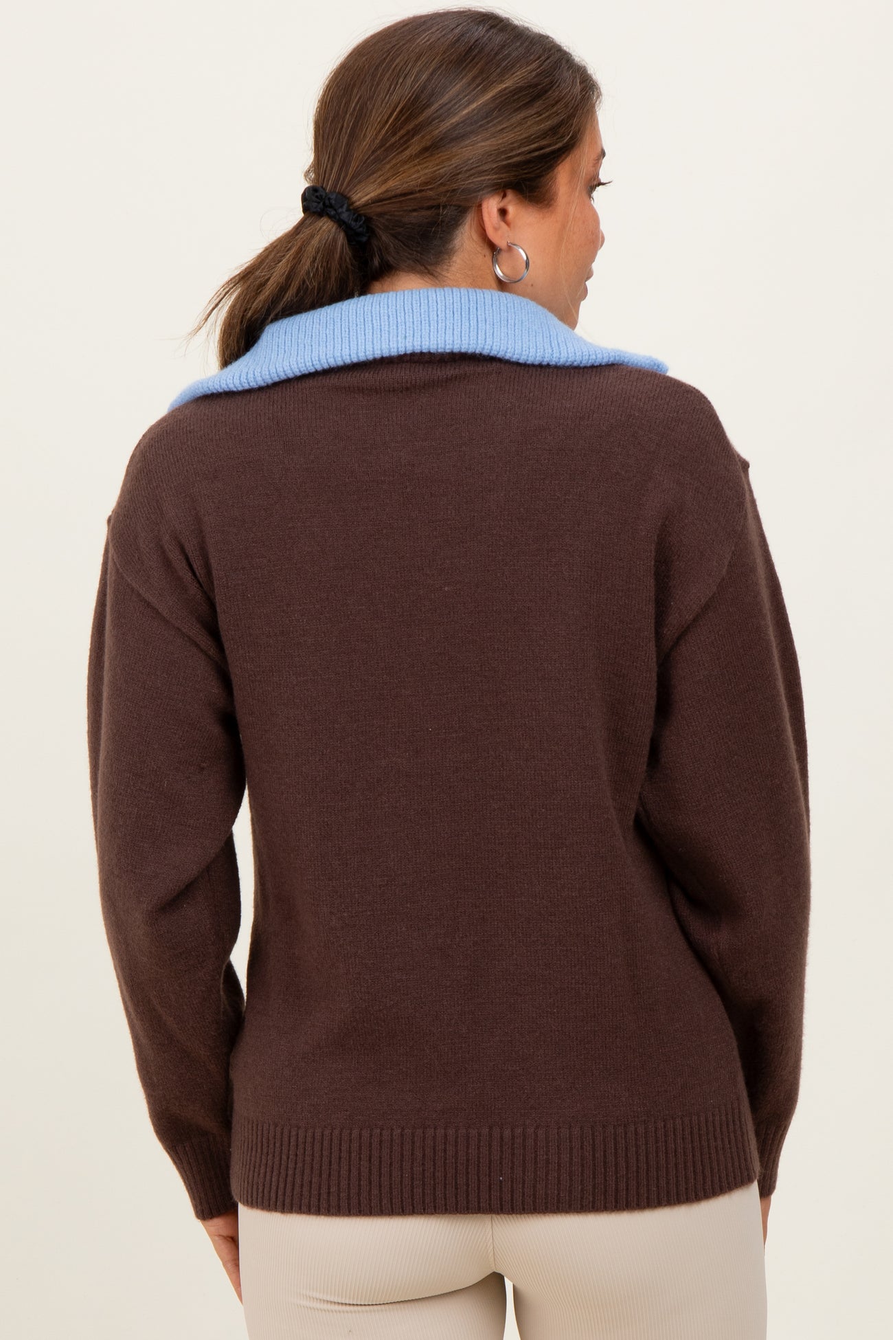 woman wearing a brown maternity sweater with a light blue collar, shown from the back