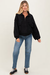 woman wearing a black zip-up maternity pullover with front pockets and relaxed fit, paired with blue jeans