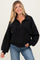 woman wearing a black maternity pullover sweatshirt with front pockets and a half zip, smiling at the camera