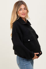 woman wearing a black maternity fleece pullover with front pockets and a baby bump visible
