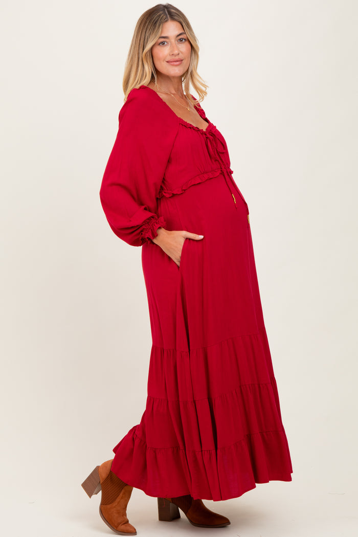woman wearing a red long sleeve maternity maxi dress with a ruffle hem and a visible baby bump