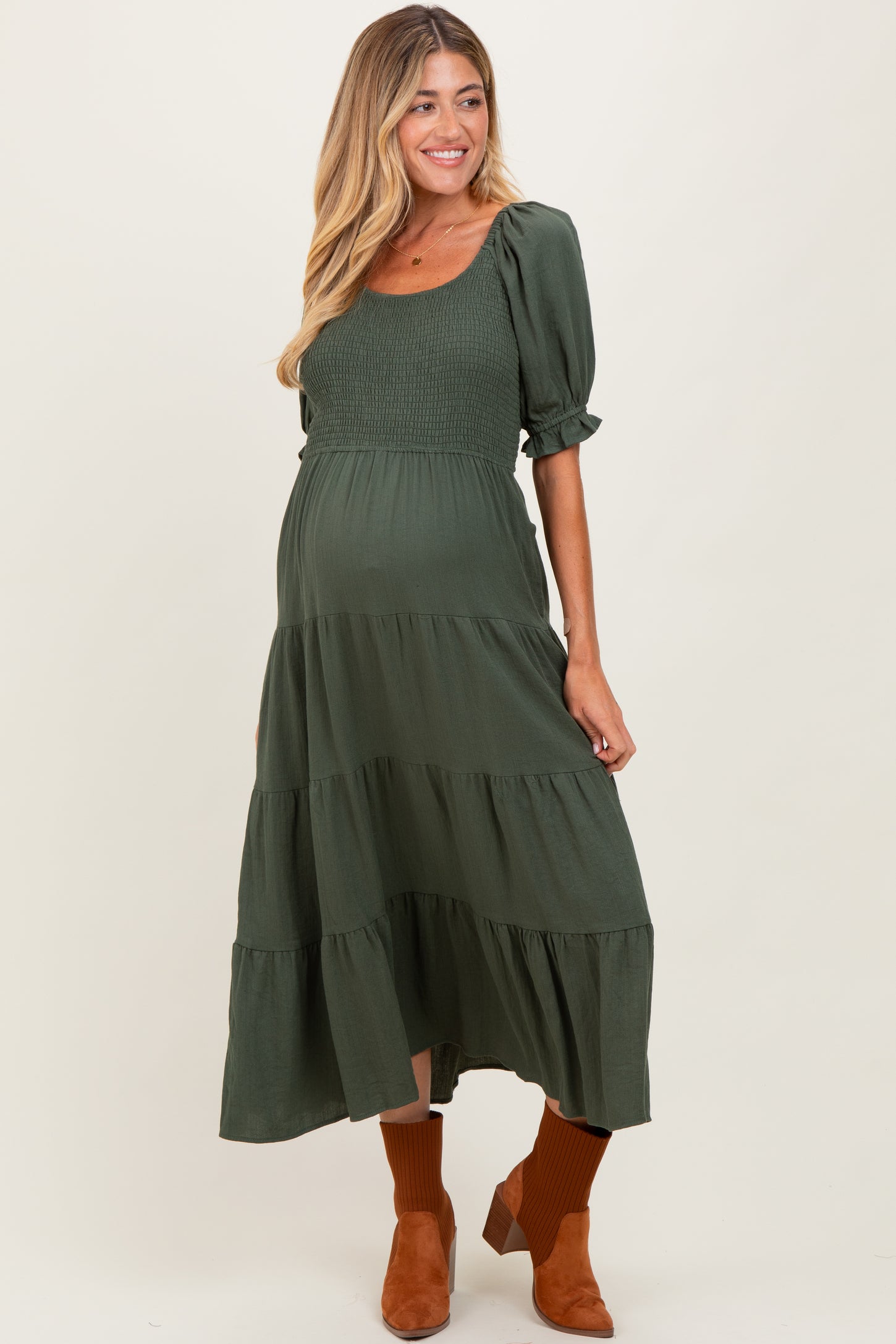 woman wearing a dark green maternity maxi dress with smocked bodice and tiered skirt, showing a baby bump